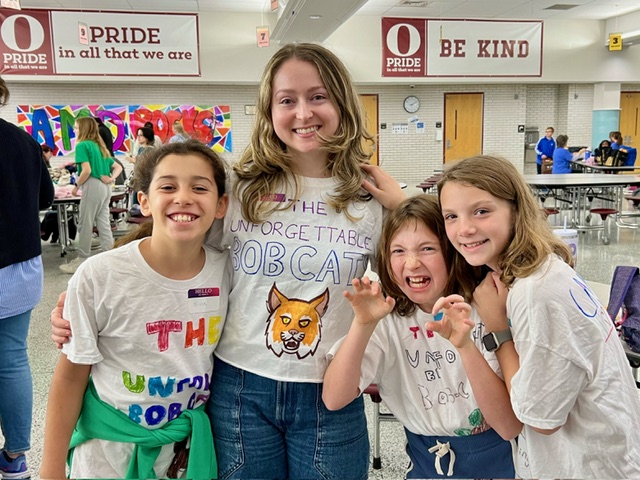 Three kids and one adult wearing team t-shirts.